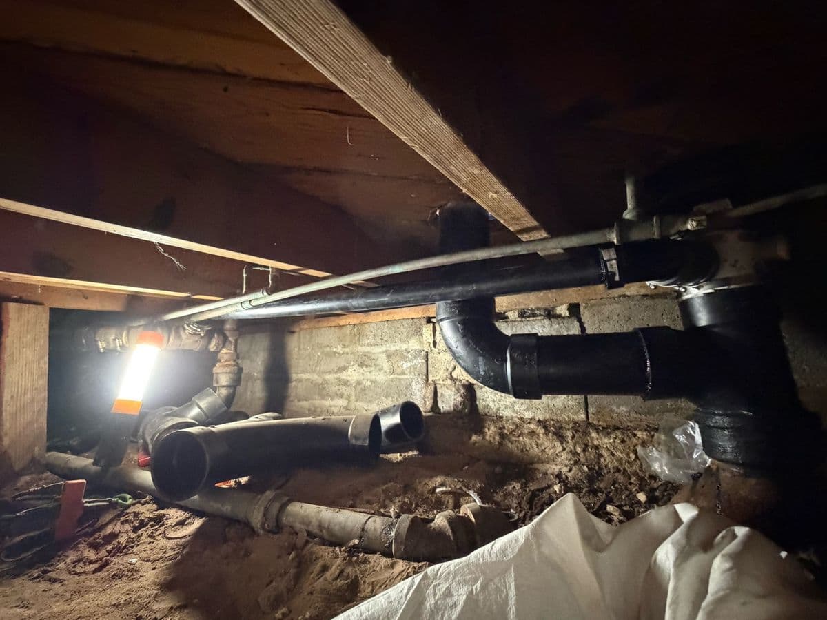 New black ABS drain lines installed in a crawlspace