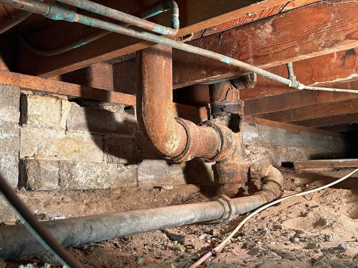 Rusted cast-iron drain line in a crawlspace