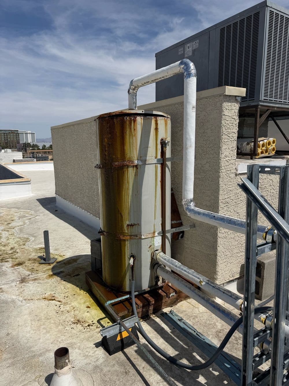 Old rusted commercial water heater on a rooftop before replacement