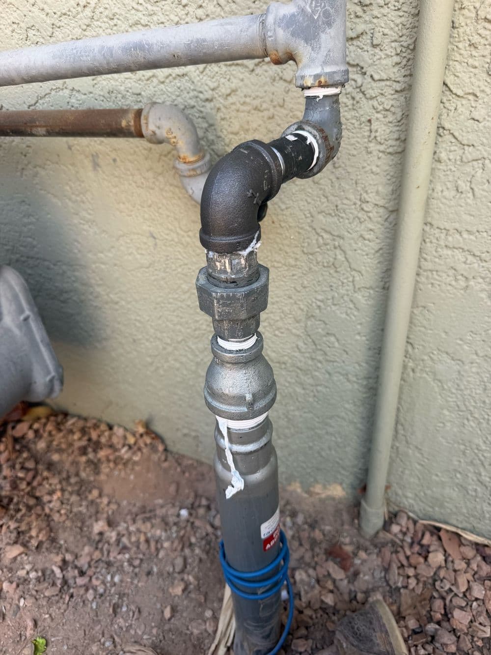 Gas riser with new black-iron fittings on the side of a house